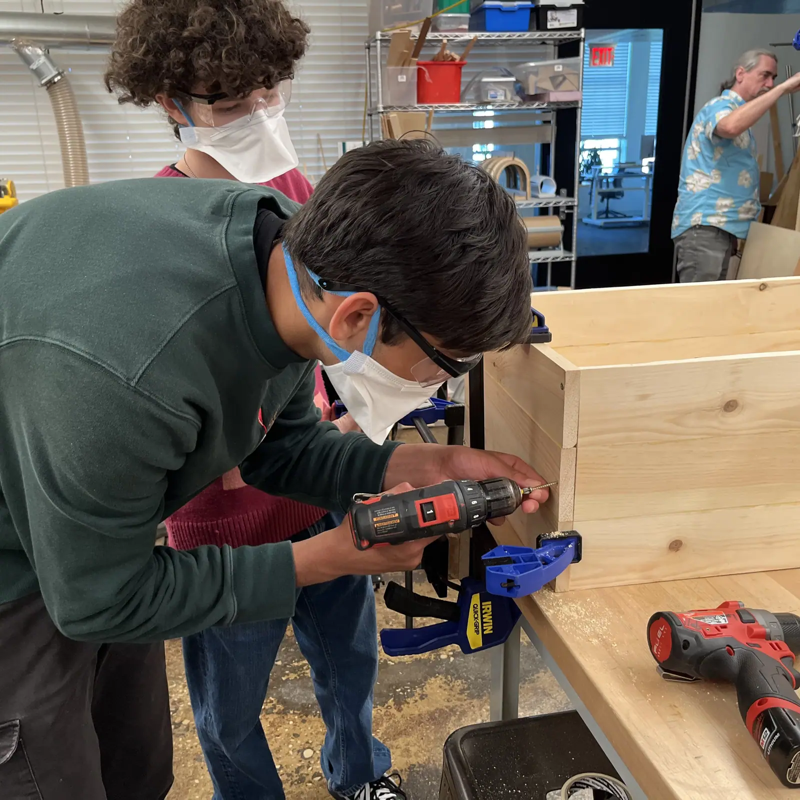 MintBox members assembling the birch frame of the Auto-Watering Planter in a workshop.
