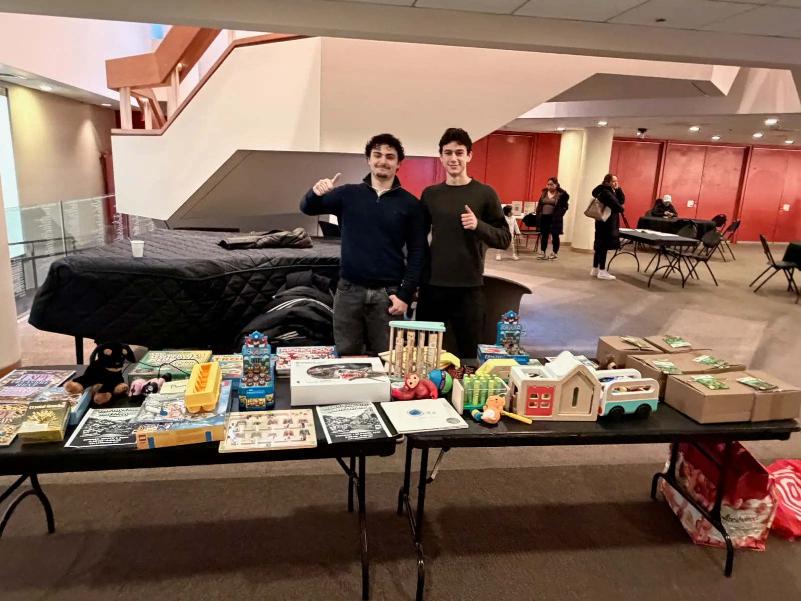 Two MintBox volunteers giving a thumbs-up behind the toy table.